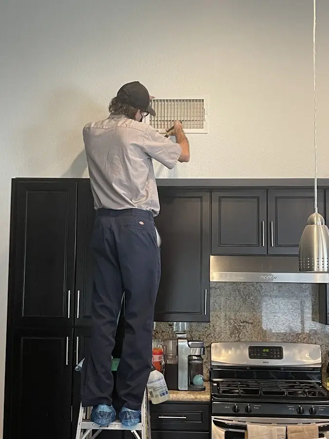 Technician inspecting an air vent during HVAC service in Kettering